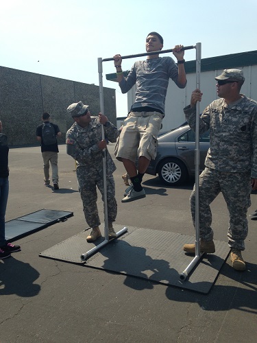 Junior Juan Carlos Alberto Soto does pull-ups to get a water bottle, while Staff Sergeants Michel and Philippi count the number of pull-ups he does. The Army visited  to create awareness of what the army is really about and to provide student with information.