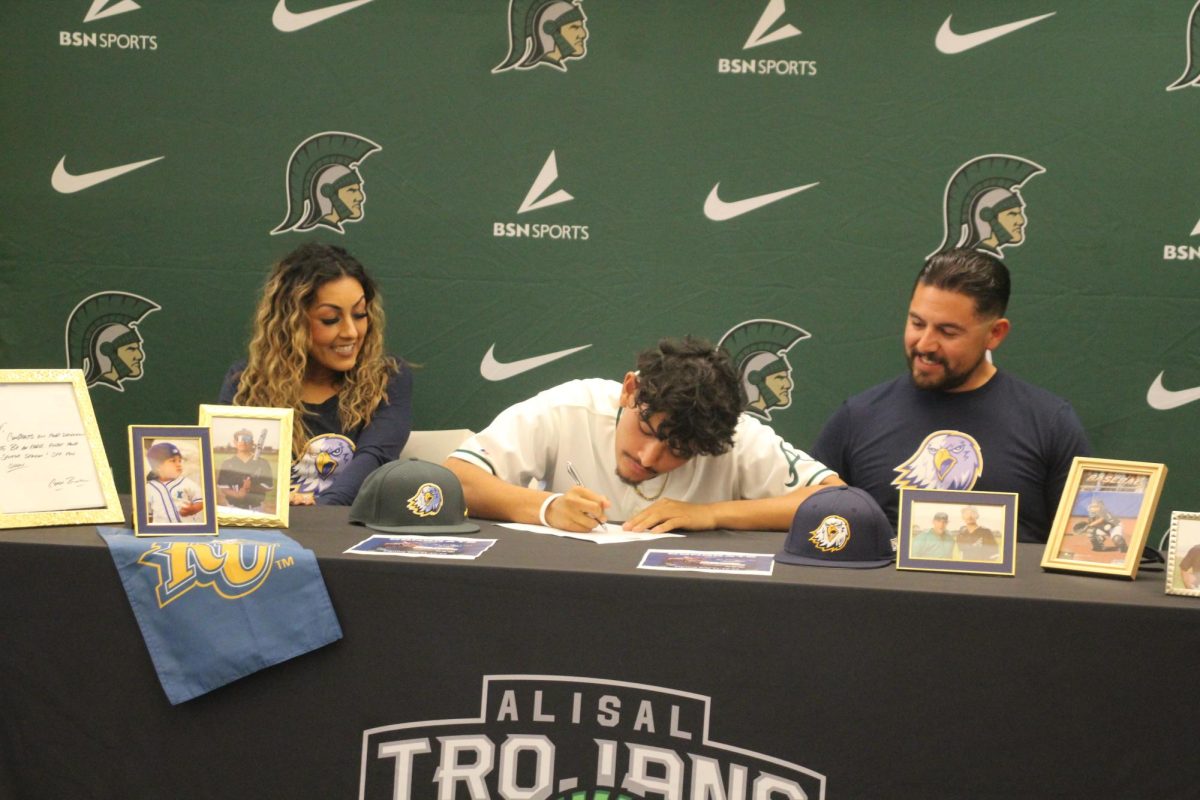 Flanked+by+his+mother+and+father%2C+senior+Xavier+Mendez+signs+his+letter+of+intent+to+play+baseball+at+Reinhardt+University+on+November+15%2C+2023.