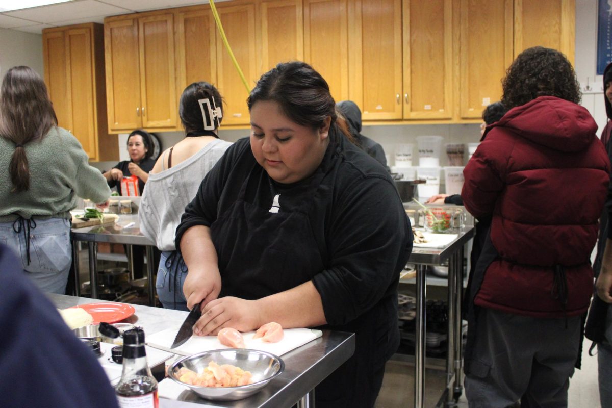 In the Advanced Culinary class, senior Alondra Orozco slices chicken to make Vietnamese dish, pho. Orozcos positive contributions to the class led her teacher, Yesenia Botello, to choose her as Student of the Quarter. “I put so much effort in class and I am glad others see that,” Orozco said.